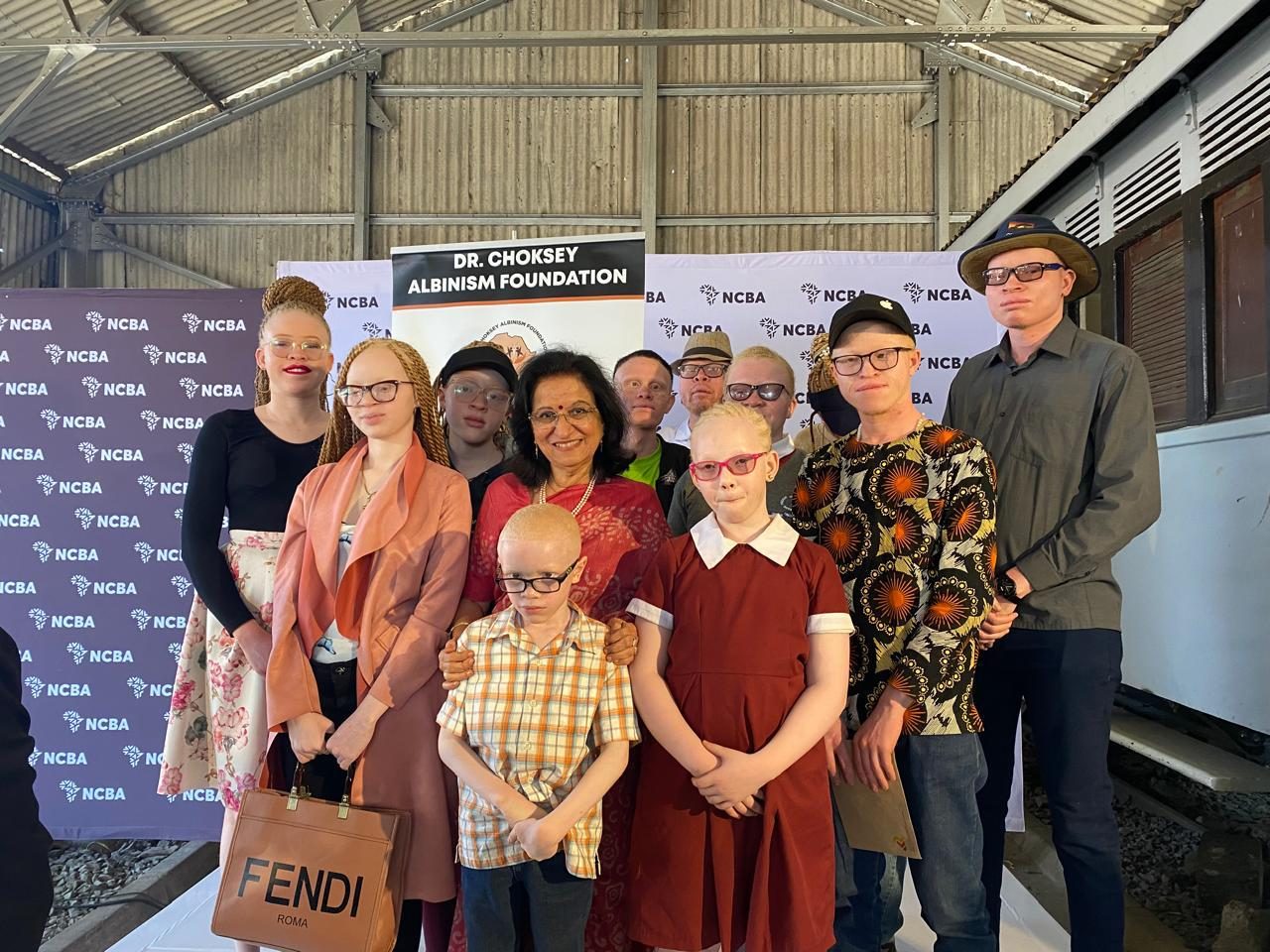 Children with albinism wearing their prescription glasses beside Dr. Prabha Choksey